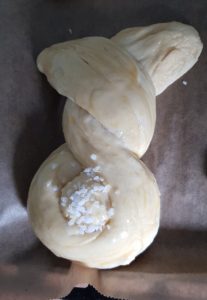 verdrehte Osterhasen mit Ei bestreichen und Hagelzucker bestreuen